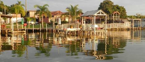 A waterfront property with multiple wooden structures, including a covered area and a dining setup.