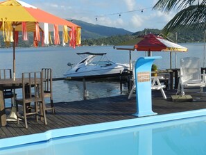 A poolside area with a dock, chairs, and umbrellas. - Recanto do Sossego em Laguna-Perrixil (Laguna)