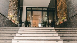 A grand staircase leading to a modern building entrance with potted plants on either side. - Ficus Suites Apartment (Hanoi)