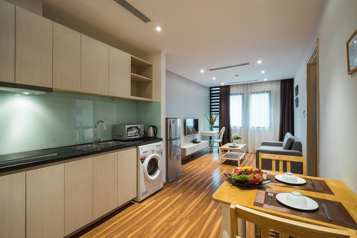 A modern kitchen with a washing machine, a refrigerator, and a dining area with a table set for two.