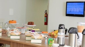 Mostra de buffet amb diversos plats i begudes, un extintor i una televisió penjada a la paret.