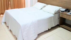 Habitació d'hotel amb un llit, una taula de nit i un telèfon.