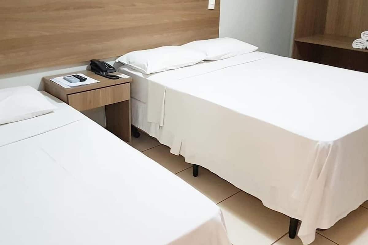 Ein Hotelzimmer mit zwei Einzelbetten, einem Holzkopfstück, einem Nachttisch mit Telefon und Lampe sowie einem Schrank.