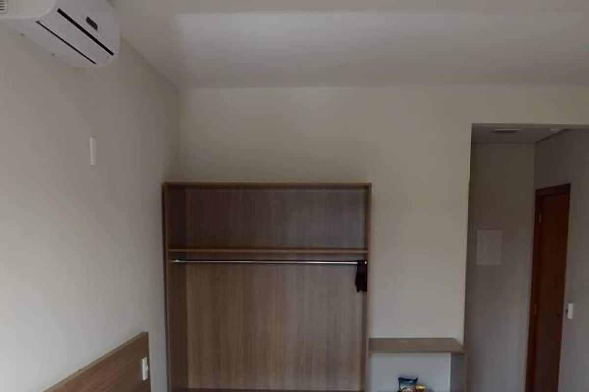 Ein Hotelzimmer mit Bett, Schrank, kleinem Schreibtisch und Klimaanlage.