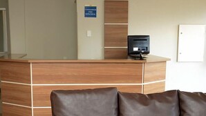Et reception område med en træreception, en sort printer og en brun lædersofa.