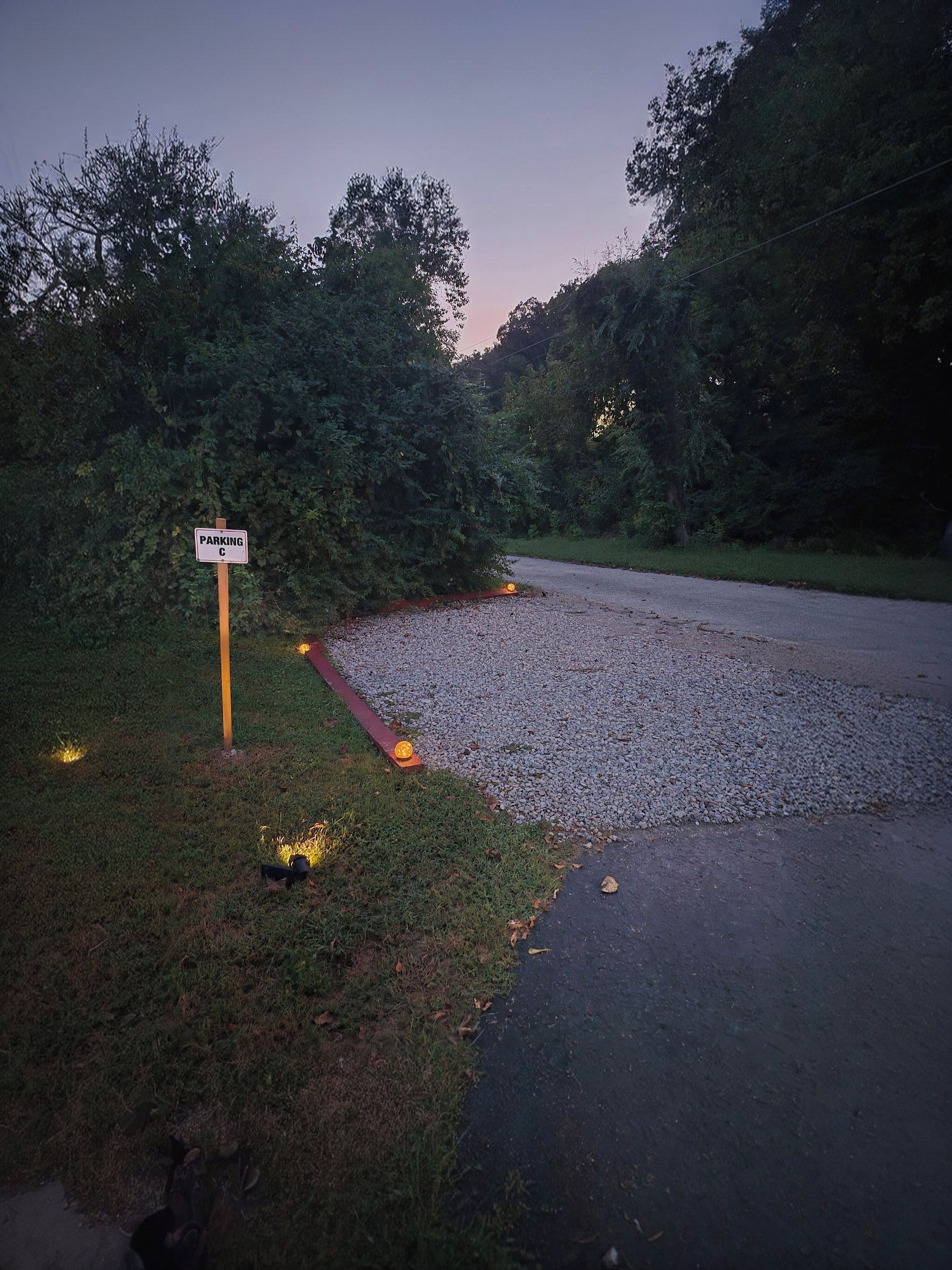 A gravel parking area with a sign indicating parking.