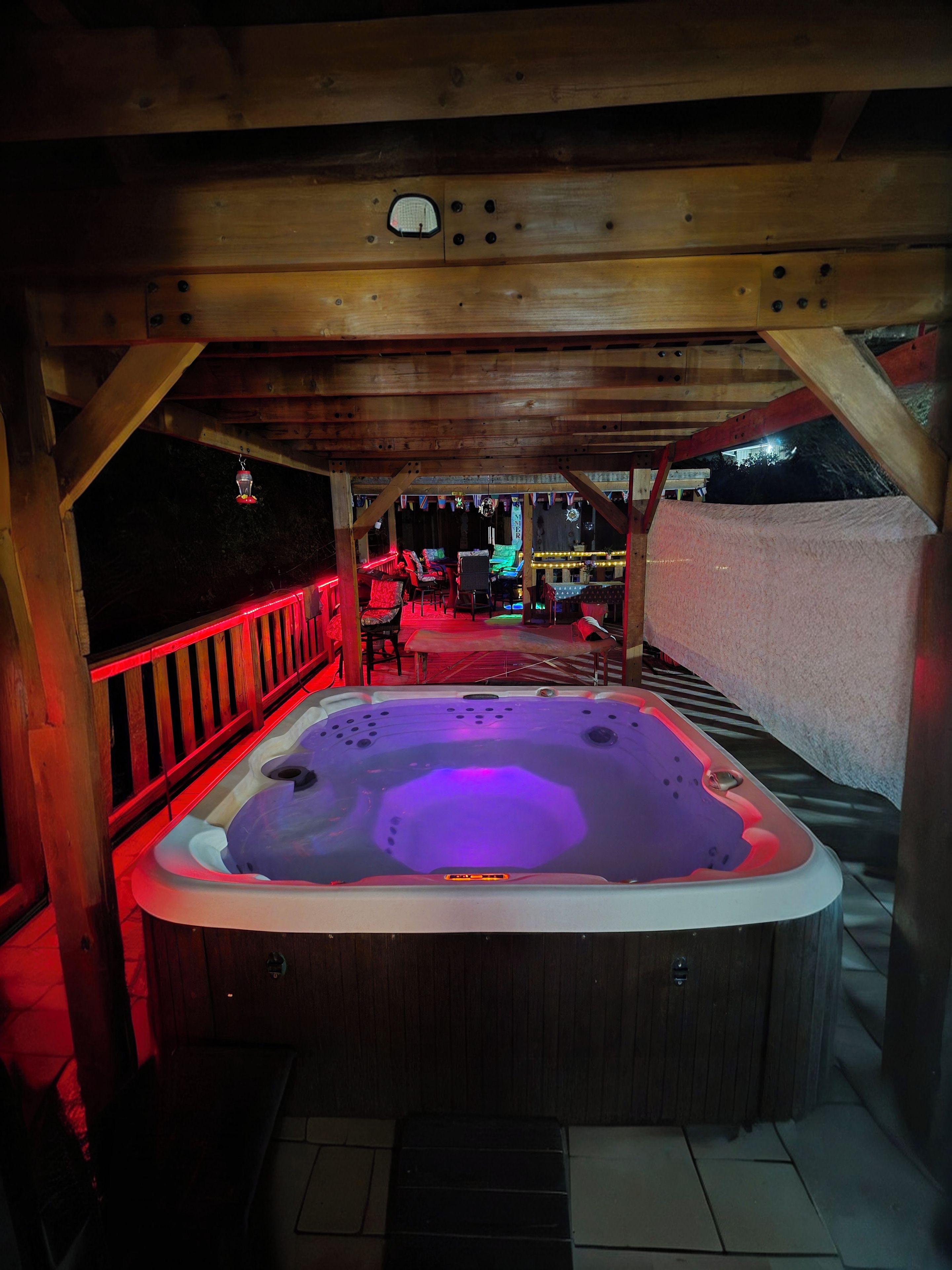 Een hottub met een houten terras en een overdekte zithoek.