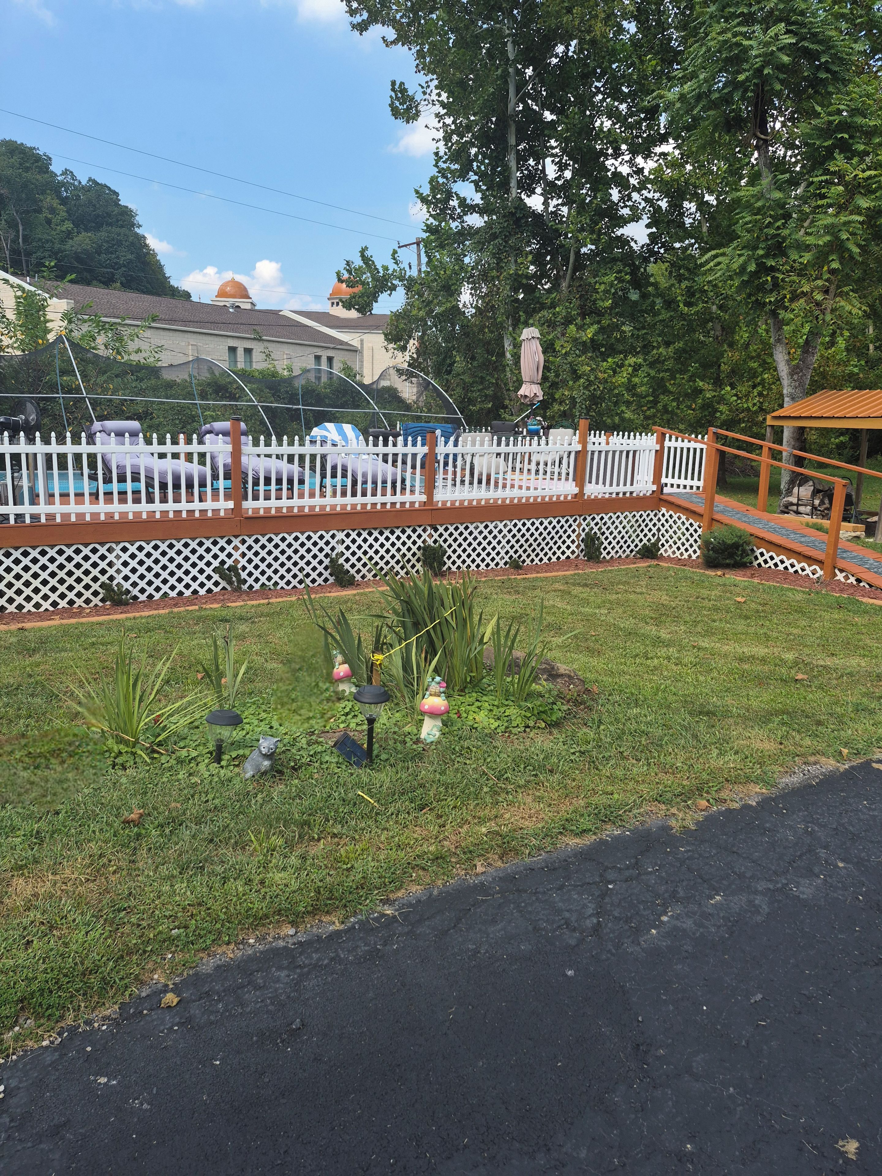 A fenced outdoor area with a pool, lounge chairs, and a gazebo.