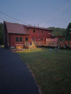 A two-story wooden building with a porch, a small deck, and a paved driveway.