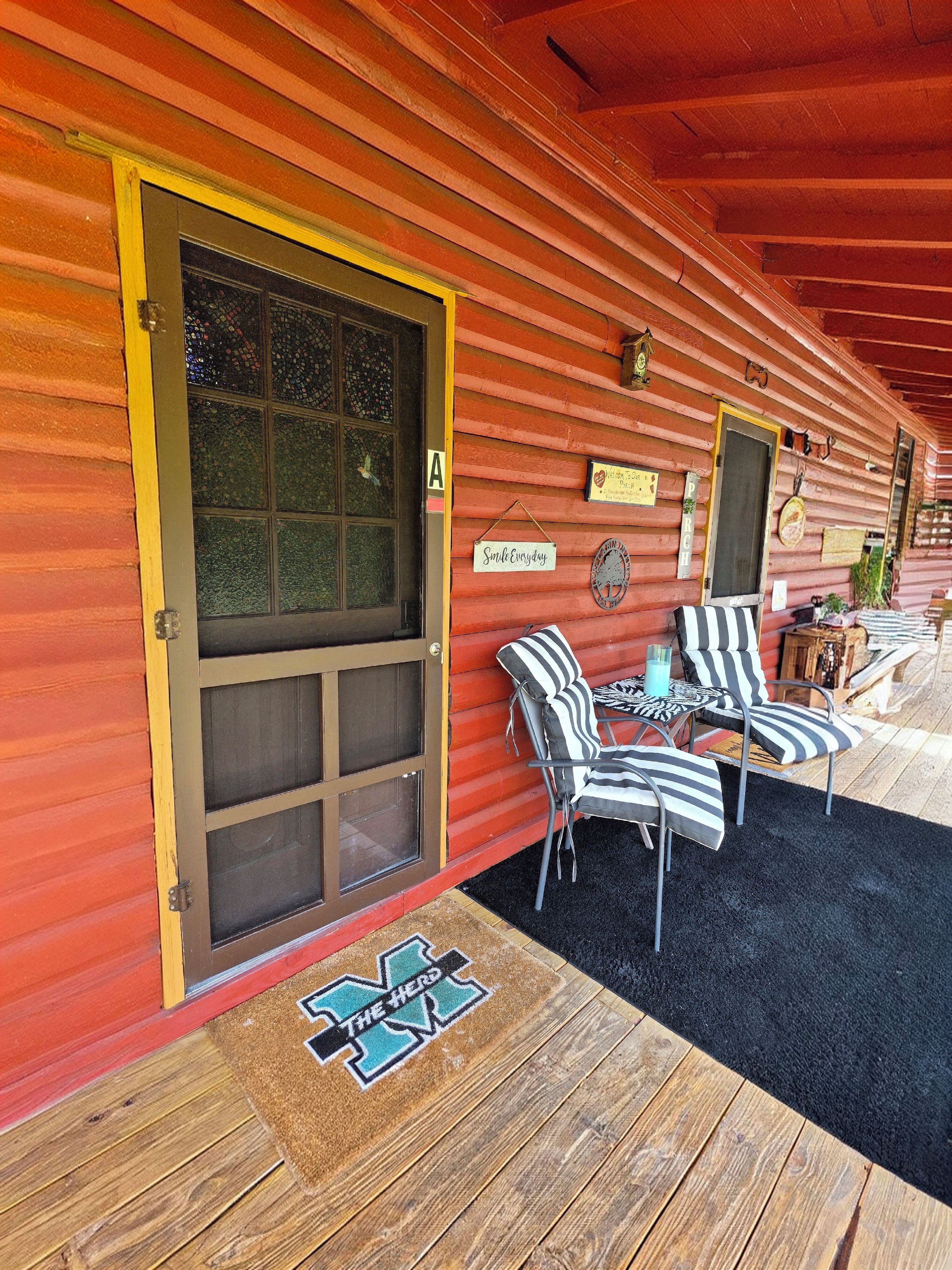 A wooden cabin with a large front door, a porch with striped chairs, and a sign that reads 'Smile Everyday.'