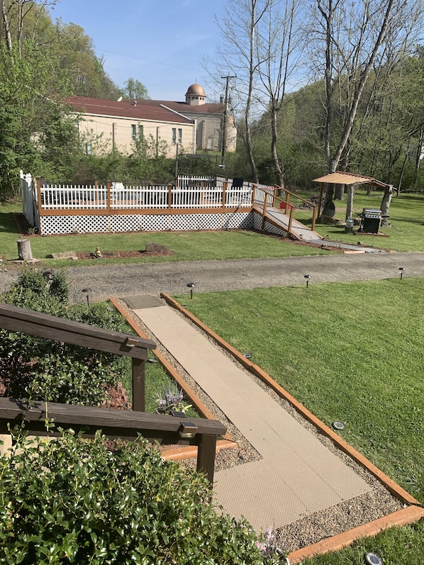 A backyard with a pergola, a wooden deck, and a fenced area with a gazebo. - Log Cabin in the Field (Huntington)