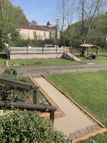 Un patio trasero con una pérgola, una terraza de madera y un área cercada con un pabellón.
