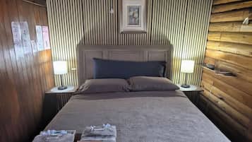 A neatly made bed with a headboard, two bedside lamps, and a framed picture above it.