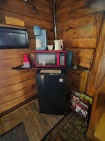 Una kitchenette compacta con microondas, cafetera y un refrigerador pequeño.