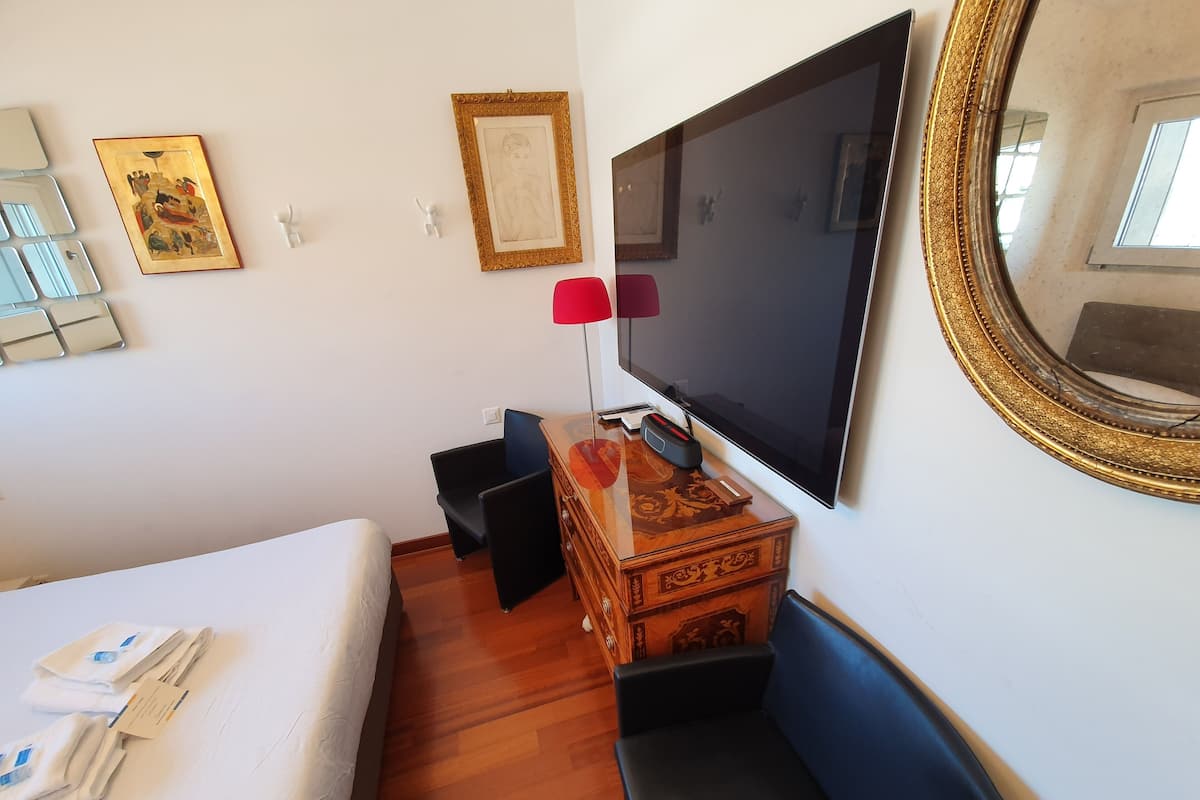Una habitación de hotel con cama, televisión, cómoda y espejo.