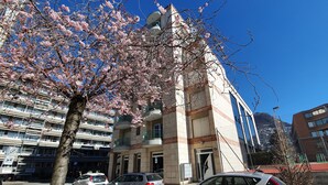 Un edificio de varios pisos con un estilo arquitectónico moderno, que destaca por una entrada imponente y un balcón.
