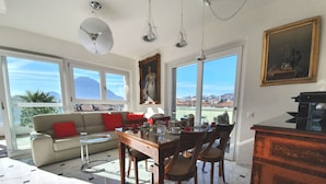 Amplia sala de estar con mesa de comedor, sillas, sofá y vistas de la ciudad a través de grandes ventanales.
