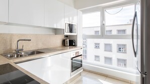 Una cocina moderna con microondas integrado, pileta de acero inoxidable y horno.