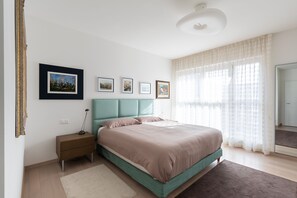 A bedroom with a bed, nightstand, and wall-mounted pictures. - Parco Apartments (Lugano)