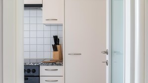 Una cocina con armarios blancos, un horno de acero inoxidable y un bloque de cuchillos en la encimera.