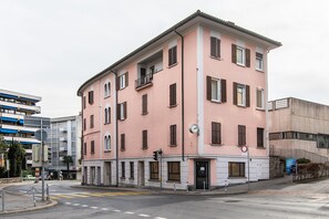A pink building with multiple windows and a balcony. - Maraini Apartments (Lugano)