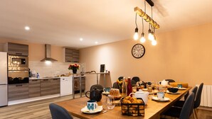 A modern kitchen with a wooden dining table, chairs, and a clock on the wall.
