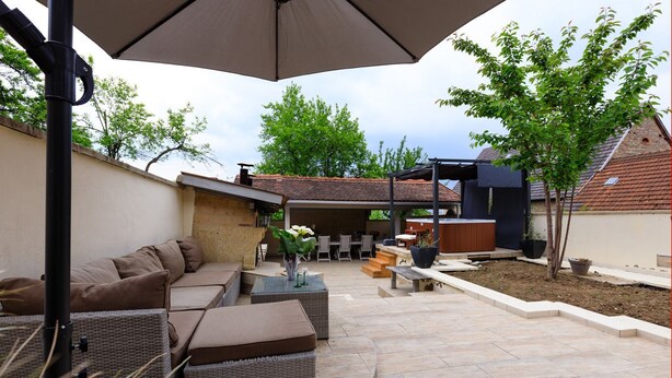 An outdoor patio area with a sofa set, a dining table, and a large umbrella.