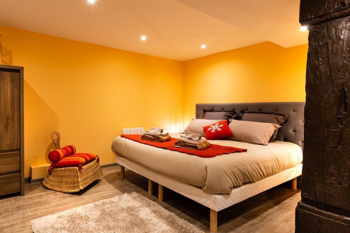 A bedroom with a bed, wooden wardrobe, and a wicker basket.