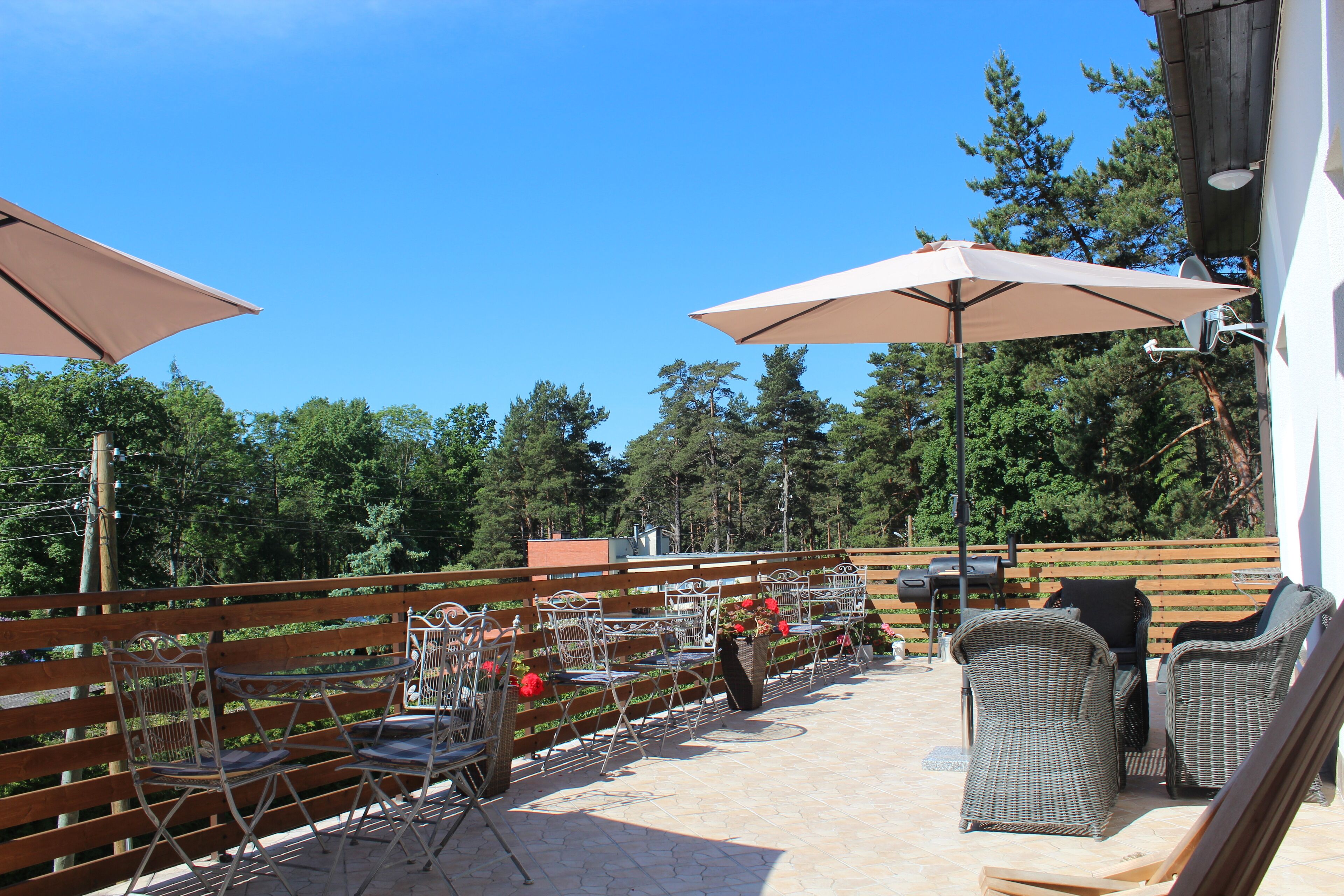 An outdoor patio with metal chairs and tables, umbrellas, and a wooden fence.