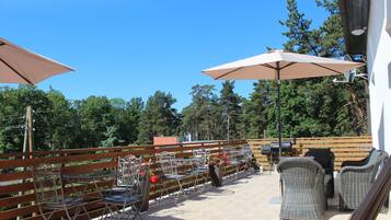 An outdoor patio with metal chairs and tables, umbrellas, and a wooden fence.