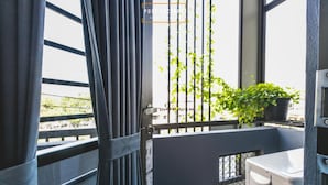 Un balcón con vista a la ciudad, una planta en maceta y una pequeña área de kitchenette.