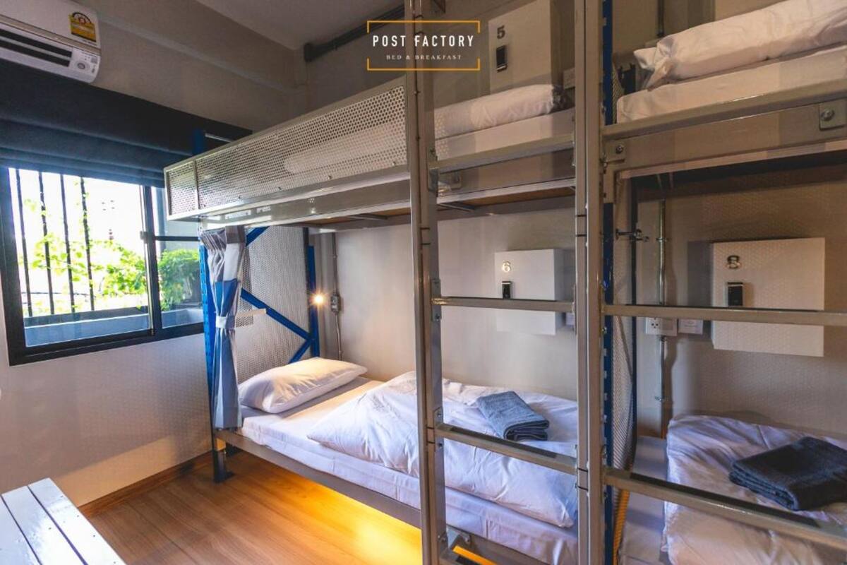 Ett rum med en våningssäng, ett fönster och en luftkonditioneringsanläggning, samt en skylt med texten ”POST FACTORY BED & BREAKFAST”.
