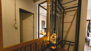 Una escalera con barandilla de madera y una botella de whisky en el rellano.