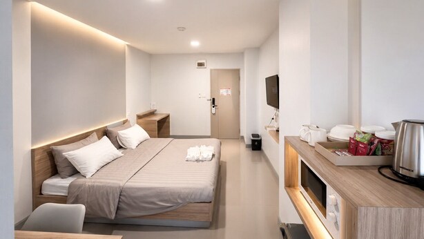 Une chambre d’hôtel moderne équipée d’un lit, d’une table de chevet, d’une télévision et d’un coin cuisine.