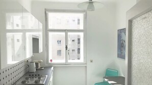 A small kitchen with a stove, sink, and a window overlooking a building. - Lovely Apartment directly at Naschmarkt (Vienna)