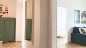 A hallway with a green cabinet, a large mirror, and a blue sofa with cushions. - Lovely Apartment directly at Naschmarkt (Vienna)