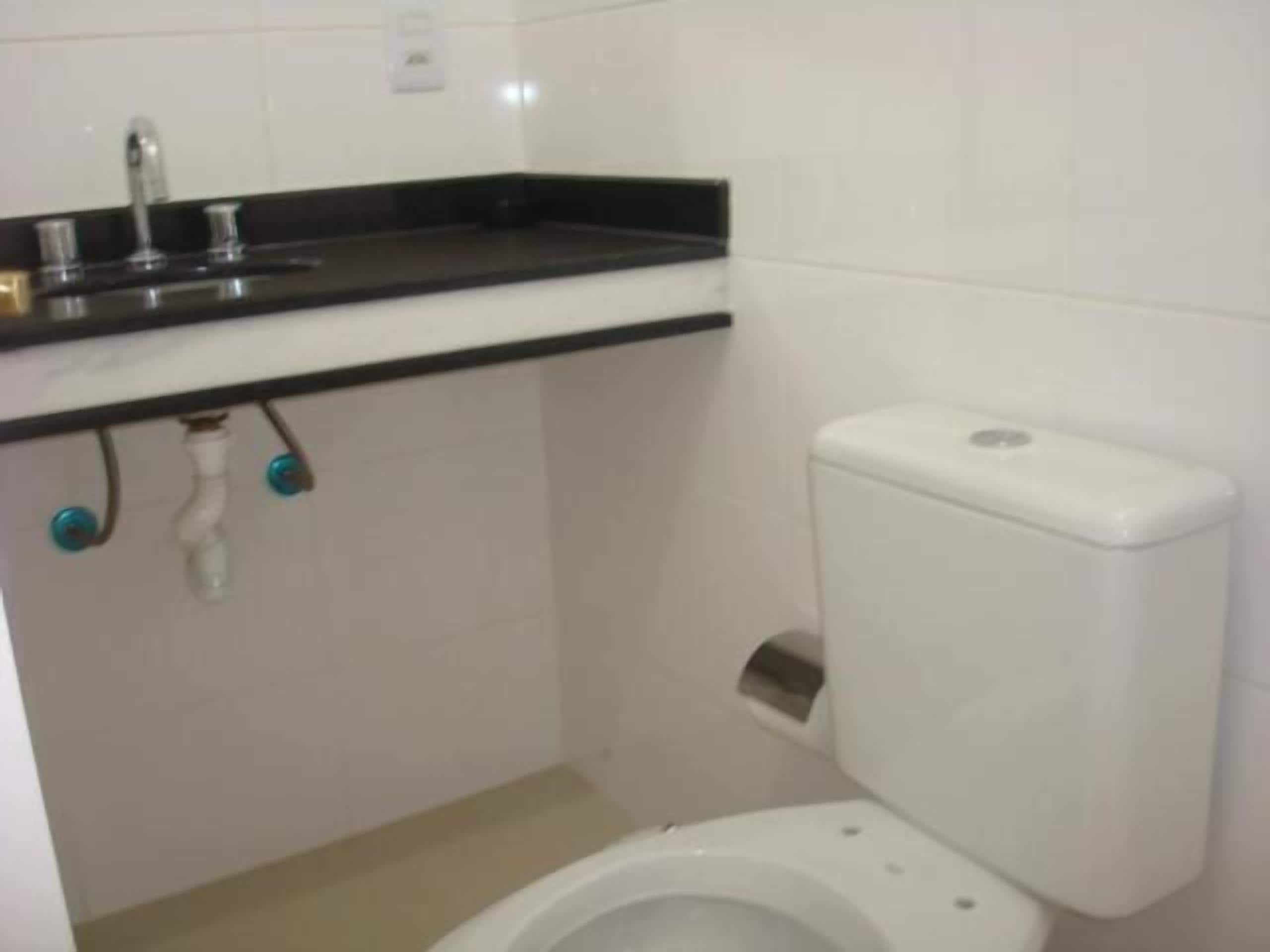 A small, clean bathroom with a toilet, sink, and white tiles.