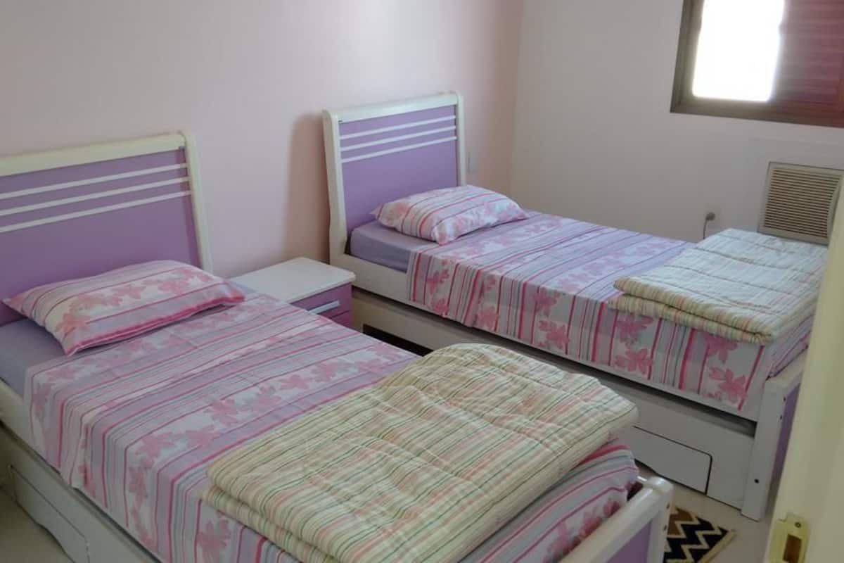 A bedroom with two single beds, each with a headboard and a bedside table.