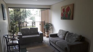 Een woonkamer met een bank, fauteuils, een bijzettafeltje en een potplant.