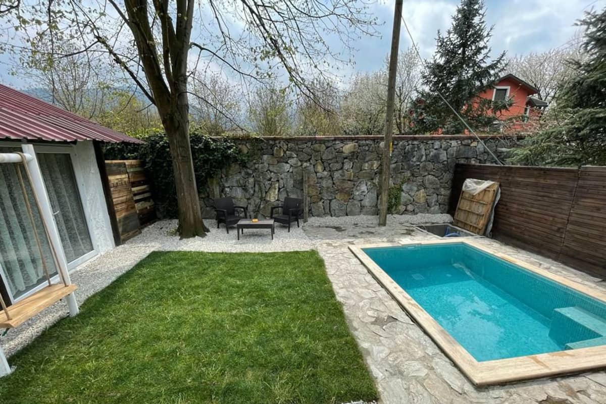 Ein Garten mit Swimmingpool, Steinmauer und Rasenfläche.