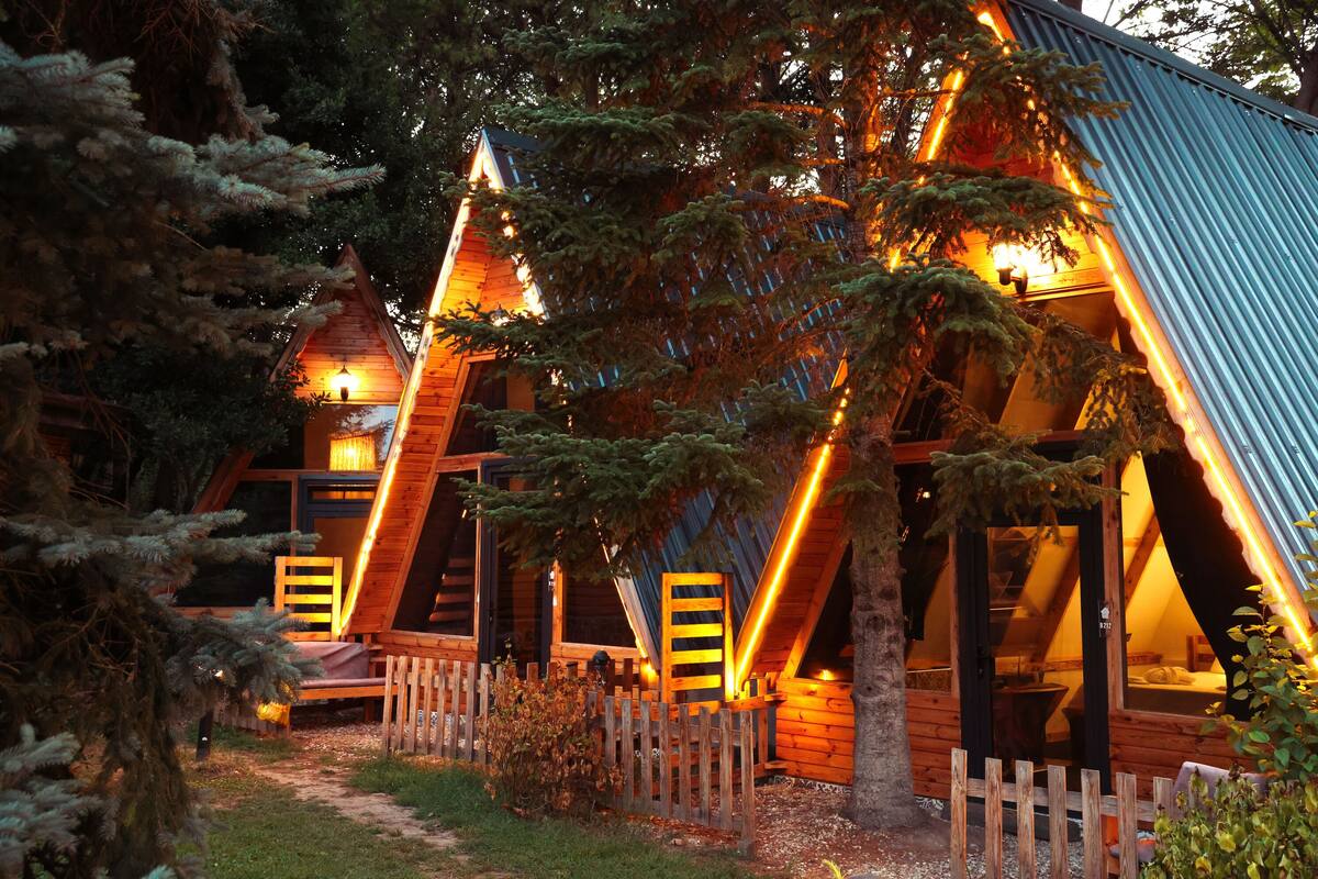Eine Holzhütte mit geneigtem Dach, umgeben von Bäumen.