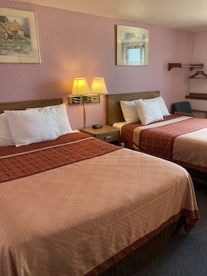Two beds with matching headboards, a nightstand with a lamp, and a chair.