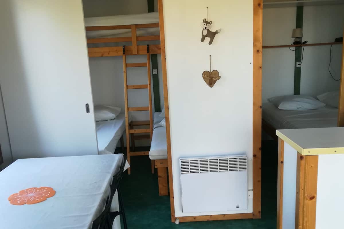 Une chambre de dortoir avec des lits superposés, un radiateur et une lampe fixée au mur.