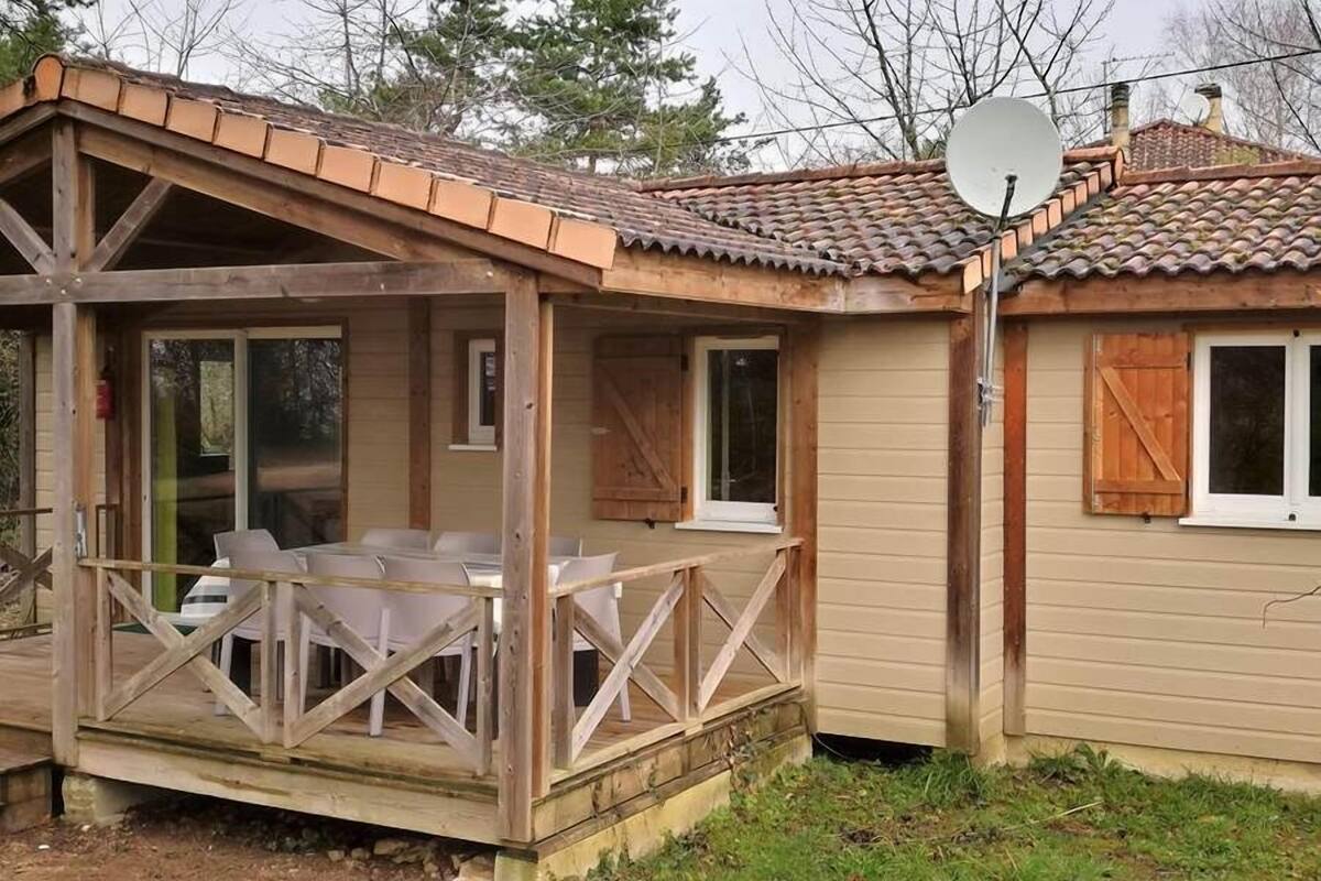 Une cabane en bois dotée d’un patio couvert, d’une antenne parabolique et d’un petit abri attenant.