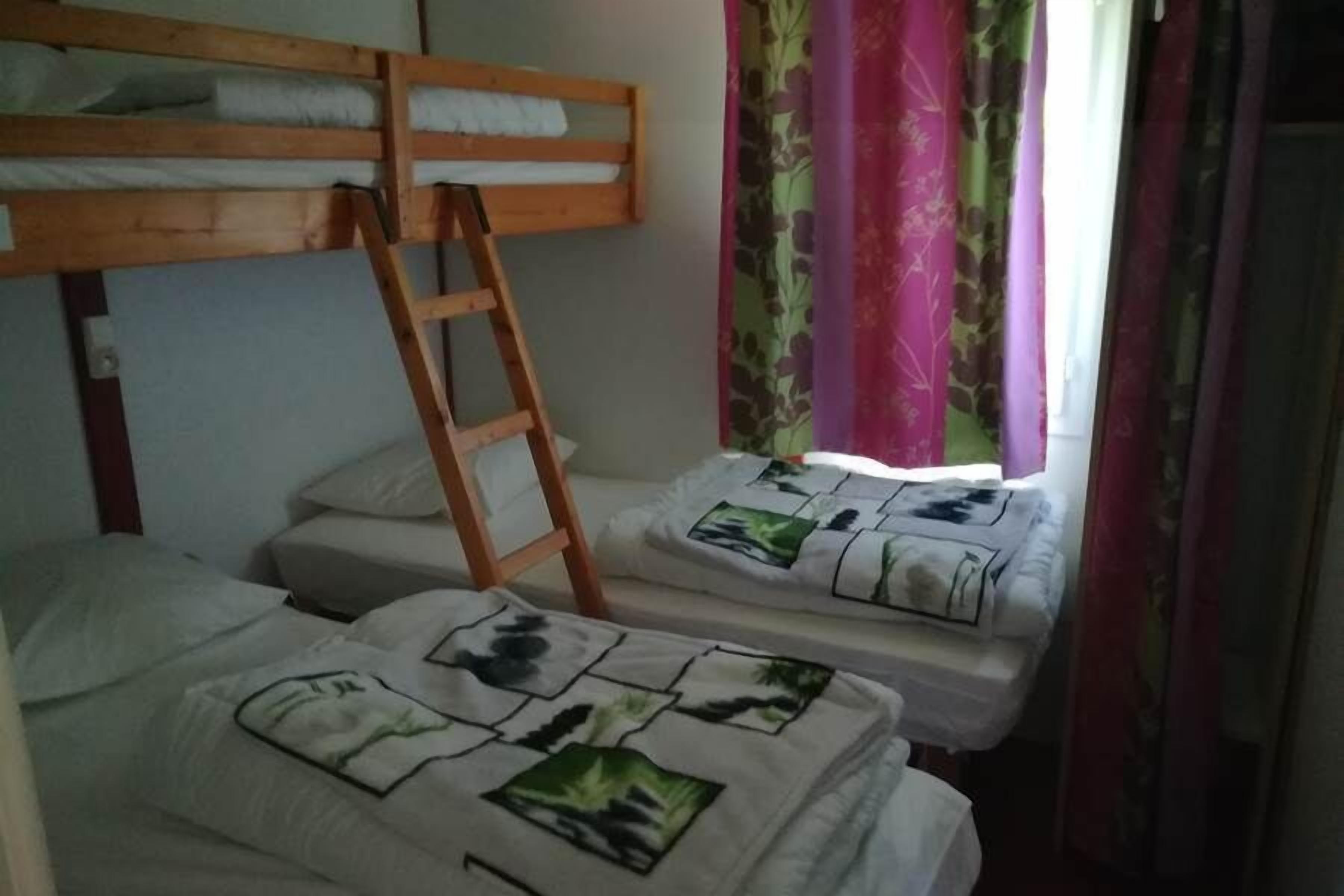 Une chambre de dortoir avec des lits superposés, une échelle et une fenêtre avec des rideaux.