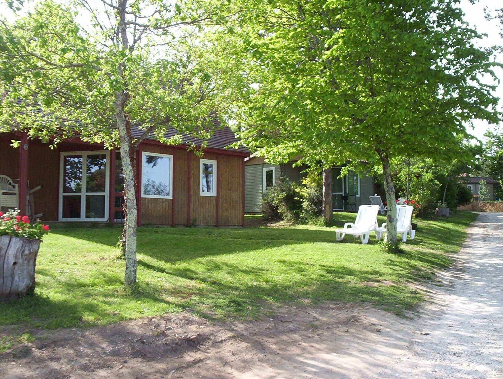 Une maison avec un jardin devant, une allée et une chaise blanche.