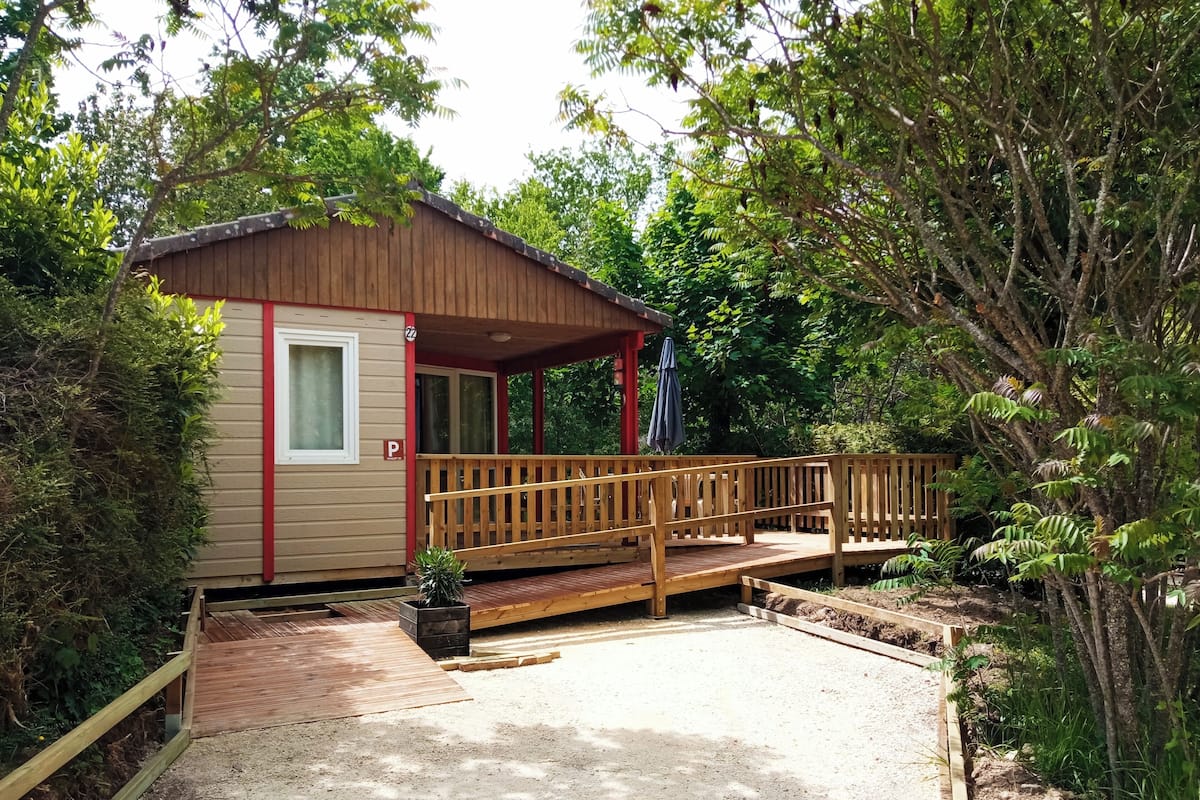 Une petite cabane en bois dotée d’un porche abrité et d’une allée gravillonnée.