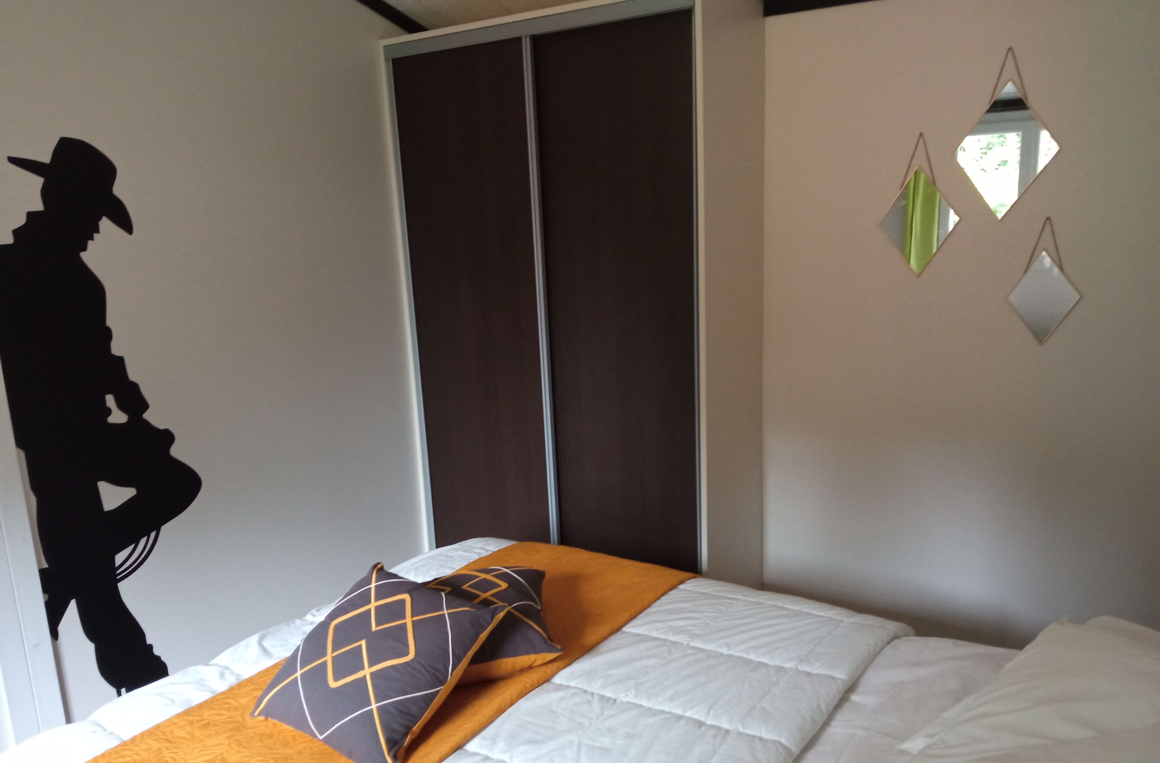 Un dormitorio con cama, armario y un adorno en la pared.