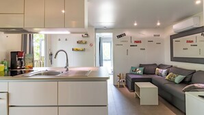 Een moderne keuken met een inbouweiland, een zithoek met een bank, en een muur met stadsnamen.