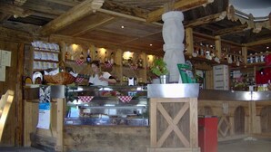 Interior rústic amb bigues de fusta, un taulell amb vitrina i diversos objectes de cuina.